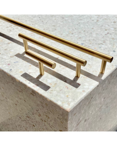 Pomello per mobile in ottone T-Bar maniglia design vista di lato su una superficie in pietra con maniglie allineate sullo sfondo