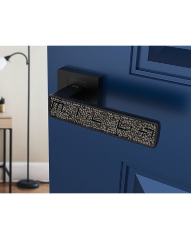 Maniglia per porta nera GLAMOUR ferramenta design vista inclinata montata su una porta socchiusa
