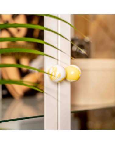 Pomello per mobile in legno di faggio giallo design vista ravvicinata leggermente inclinata montato su una porta vetrata