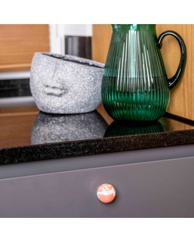 Pomello per mobile in legno di faggio rosso ciliegia design fissato su una facciata di mobile grigio sotto un piano di lavoro