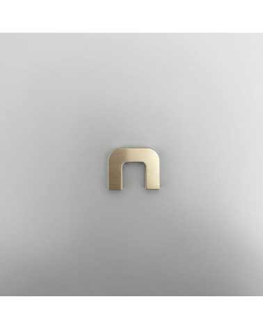 Maniglia per mobile in oro lucido ISA XS maniglia design vista frontale su superficie grigia