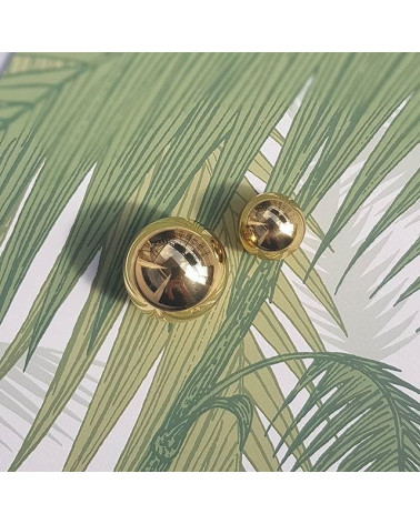 Pomello per mobile in oro lucido ODETE maniglia design posata su uno sfondo a motivo