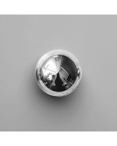 Pomello per mobile in cromo lucido ODETE M maniglia design posata su una superficie grigia