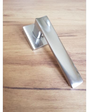 Maniglia per porta moderna DIUNA design posata su pavimento a motivo legno