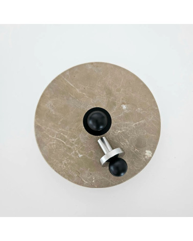 Pomello per mobile nero/cromo lucidato POLA design vista dall'alto posato su una piastra rotonda in marmo