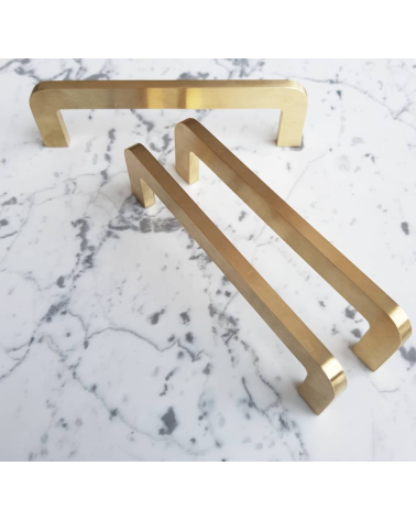 Maniglia per mobile in ottone spazzolato ISA maniglia design trio posata su una superficie con motivo