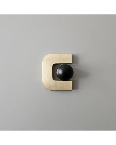 Maniglia per mobile in oro lucido ISA XS design con sfera nera posizionata all'interno dell'apertura