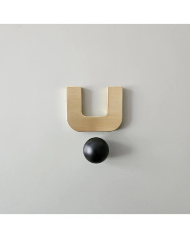 Maniglia per mobile in oro lucido ISA XS design con sfera nera vista frontale su superficie chiara