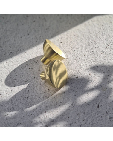 Pomello per mobile oro lucido LUNA M maniglia design posata su un cemento
