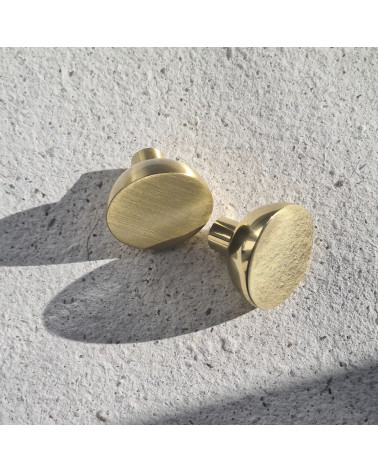 Pomello per mobile oro lucido LUNA M maniglia design vista ravvicinata posata su una piastra testurizzata