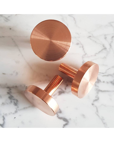 Pomello per mobile in ottone NENA M maniglia di design appoggiata su una superficie marmorizzata
