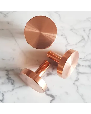 Pomello per mobile in ottone NENA M maniglia di design appoggiata su una superficie marmorizzata