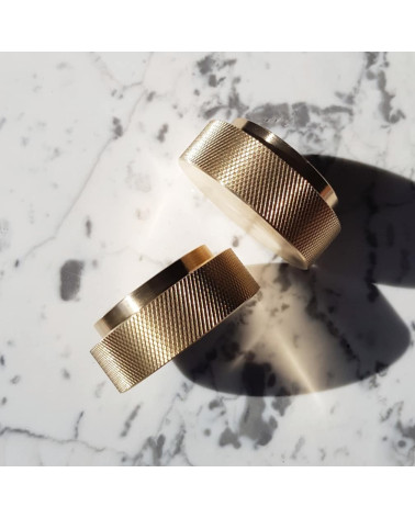 Pomello per mobile oro opaco TOVE maniglia design inclinata vista dall'alto su una superficie marmorizzata bianca con ombre
