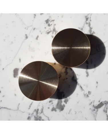 Pomello per mobile oro opaco TOVE maniglia design posata su una superficie marmorizzata bianca