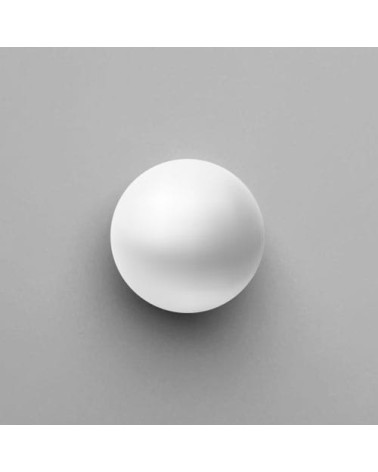 Pomello per mobile bianco ODETE maniglia design vista dall'alto posato su una superficie grigia