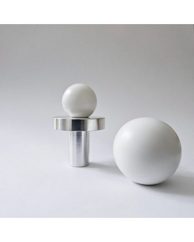 Pomello per mobile bianco ODETE maniglia design vista frontale posato su una superficie grigia