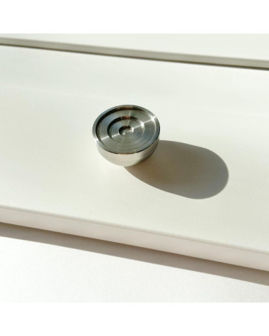Pomello per mobile in acciaio inossidabile modello 02 maniglia design posato su una superficie illuminata che proietta un'ombra