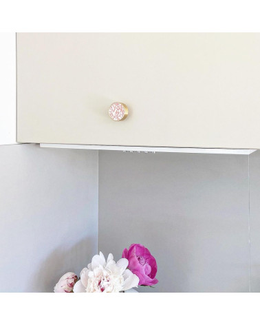 Pomello per mobile in ottone e Pink Terrazzo maniglia design installata su un mobile con fiori rosa in basso