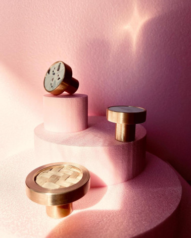 Pomello per mobile in ottone ed erbari marini maniglia design messa in evidenza su un espositore rosa