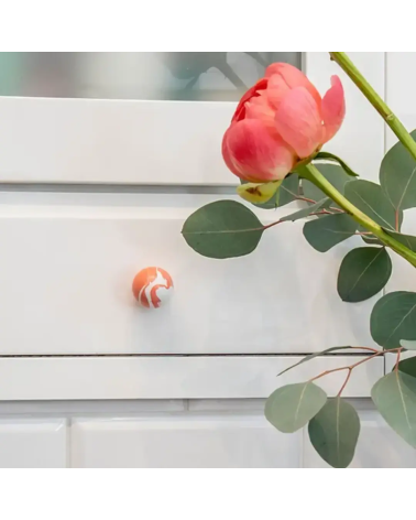 Pomolo per mobile in legno di faggio rosso ciliegia maniglia design montato su un mobile accompagnato da una rosa posata sopra