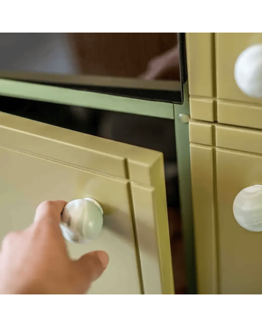 Pomello per mobile in legno di faggio Mistel maniglia design fissata su una porta aperta tenuta da una mano