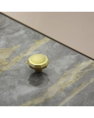 Pomello per mobile oro opaco CAMPANA maniglia design posato su una superficie piana con sfondo strutturato