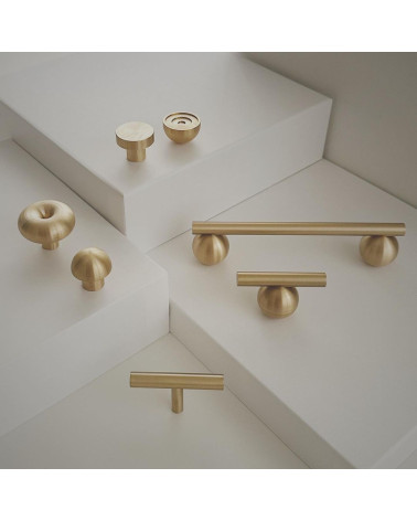 Pomello per mobile in ottone modello 04 maniglia design posizionato su una superficie chiara a scalini