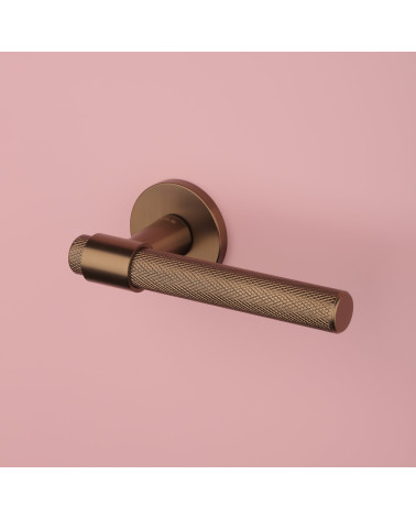 Maniglia per porta marrone chiaro GOYA design vista dall'alto inclinata su sfondo rosa