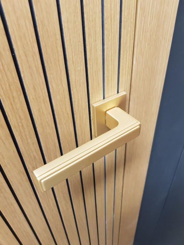 maniglia per porta dorata opaca su una porta in legno